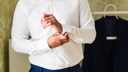 Business man fastening buttons on shirt sleeve at home close-up