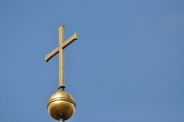 Ein goldenes Kreuz vor blauen Himmel
