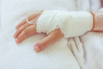 Saline intravenous (iv) drip in a child's patient hand.