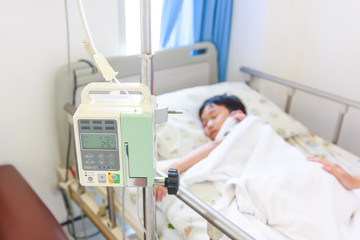 Asian boy lying on sickbed with infusion pump intravenous IV drip