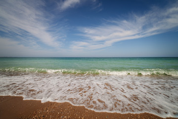 Oceanside under blue sky with clouds