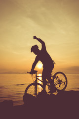 Fototapeta na wymiar Healthy lifestyle. Silhouette of bicyclist riding the bike at seaside.