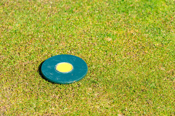 Circular marker lying on tee on a golf course. Nicely cut grass surround it. Copy space. - 108447380