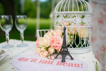 Decoration of wedding table. Wedding rings lie on the table. Figurine of the Eiffel tower. Cage...