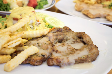 BBQ pork steak with sauce, french fries and salad [blur and select focus background]