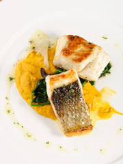 Fine dining Seabass fillets on carrot potato purree and spices