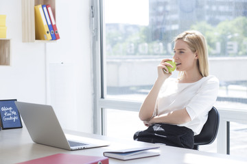 Businesswoman having healthy snack, eating apple