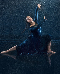 The young beautiful modern dancer dancing under water drops