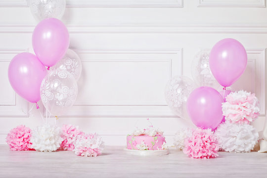 Festive cake, pompons and balloons. White and pink color. Birthd