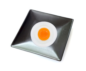 fried egg on black dish isolated on white