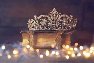 low key image of decorative crown on old book. vintage filtered