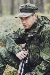 young soldier or hunter with gun in forest