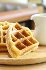 Waffles on a white wood plate.