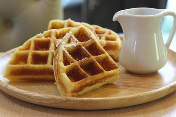 Waffles on a white wood plate.