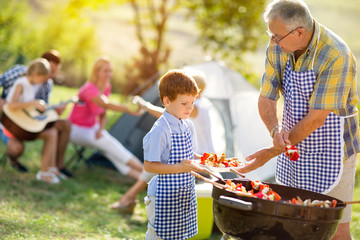 grandfather giving grandson grilled meat.