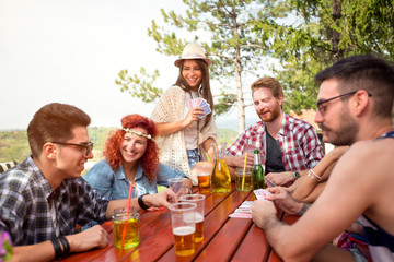 Youth enjoying with friends and card game in forest