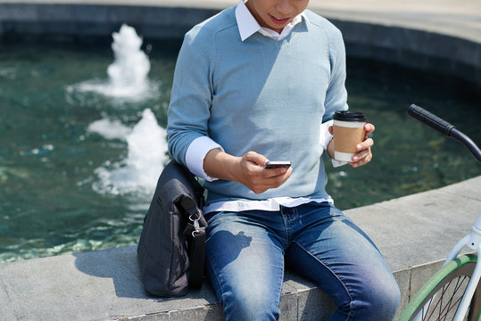 Cropped image of guy using application on his phone when resting outdoors