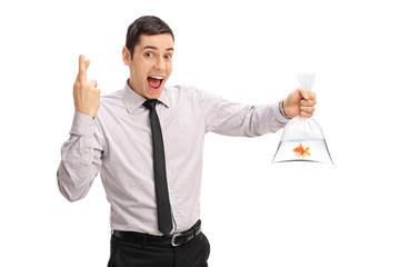 Man holding a goldfish and crossing fingers