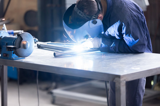 Man in mask welding iron bars