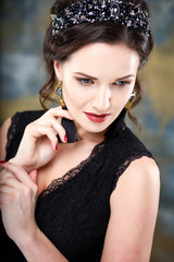 Obraz premium Elegant young woman with perfect makeup and hair style in a black dress with diadem and earrings. Beauty fashion portrait with accessories