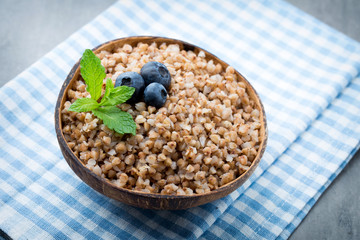 Buckwheat porridge in a bowl with mint leaves and blueberries.