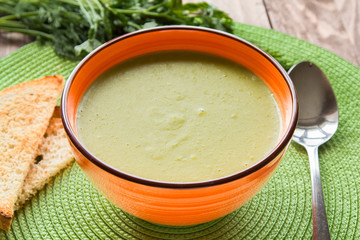 Pea soup in an orange plate with crackers
