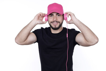 Junger Mann mit schwarzem T-Shirt und pink Kopfhörern und Basecap hört Musik 