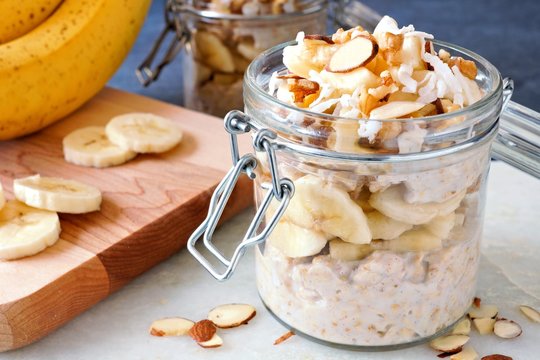 Healthy overnight oats with bananas and nuts in glass canning jars