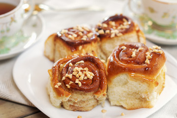 Obraz na płótnie Canvas Sweet buns with cinnamon, nuts and caramel syrup