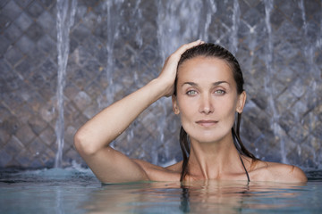 belle femme sous des chutes d'eau dans une piscine