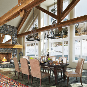 Luxurious open floor cabin interior dinning room design with roaring stone fireplace and winter scenic background. Photo realistic 3d rendering