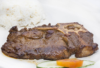 T Bone steak with rice and sauce on a white plate in a restaurant