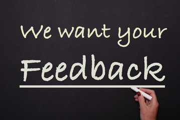 Fototapeta premium woman is writing on blackboard we want your feeback