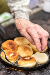 Grandmother frying donuts on firewood stove