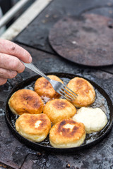 Grandmother frying donuts on firewood stove