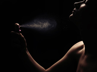 Woman with perfume on black background