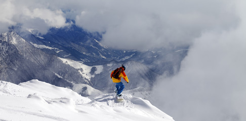 Snowboarder on off-piste slope an mountains in fog