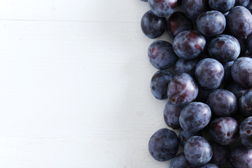 Fresh plums on the white wooden background