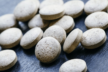 Brewer's yeast tablets on a dark background, selective focus, sh