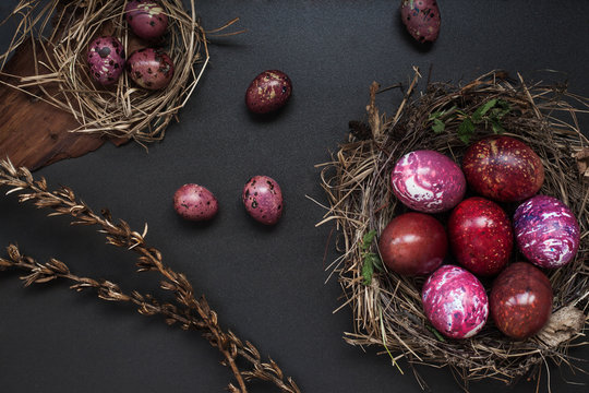 Still life of red chicken and quail eggs on black wooden background