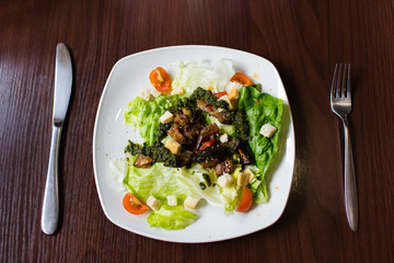 Vegetable salad on white plate on wooden table. Lenten menu