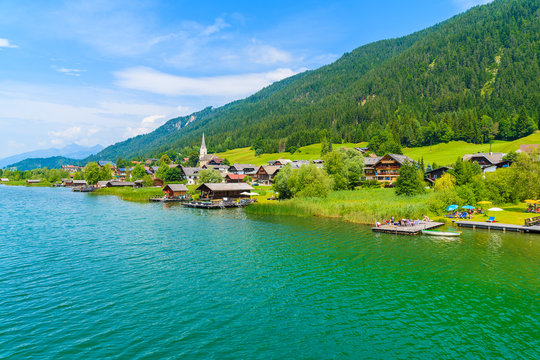 A view of beautiful green water Weissensee alpine lake and village in summer landscape of Alps Mountains, Austria