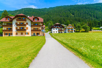 Road in alpine village with traditional houses near Weissensee lake in summer landscape of Carinthia land, Austria