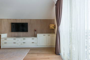 White wooden commode with tv unit near big window
