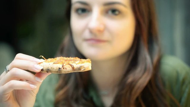 Pretty girl sitting in the restaurant and eating pizza
