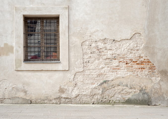 Obraz premium abandoned grunge cracked brick stucco wall with a window grilles