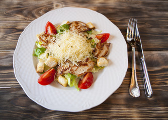 Fresh caesar salad on white bowl with parmesan cheese and chiken