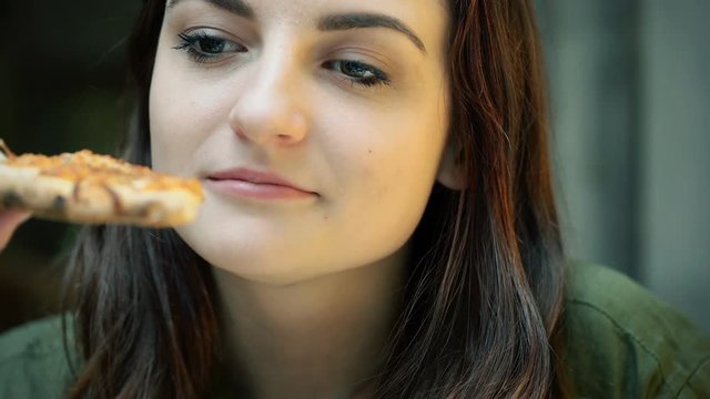 Pretty girl sitting in the restaurant and eating pizza
