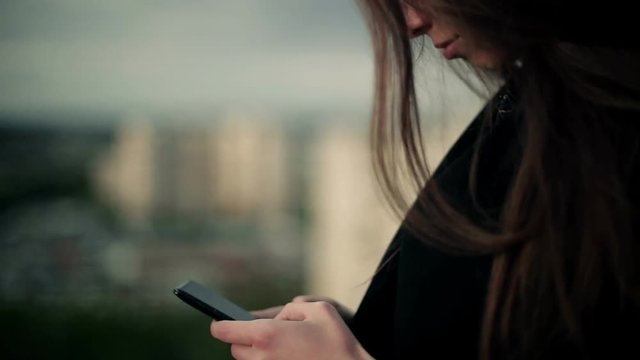Young woman uses a smartphone on the roof