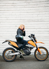 Fototapeta na wymiar Young woman on motorcycle talking on mobile phone 